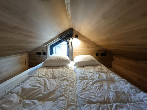 Slaapruimte met twee eenpersoonsbedden in Tiny House op Gulperberg, Nederland, houten muren en dakraam.