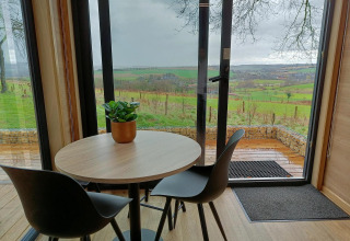 Ronde tafel met twee stoelen en een plant, uitzicht vanuit Tiny House op Gulperberg in Nederland.