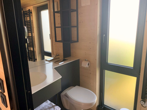 Modernes Badezimmer im Tiny House am Gulperberg, Niederlande, mit großen Fenstern und Holzdekor.