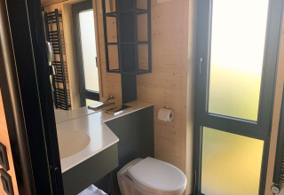 Modernes Badezimmer im Tiny House am Gulperberg, Niederlande, mit großen Fenstern und Holzdekor.