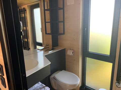 Bagno moderno nella Tiny House al Gulperberg, Paesi Bassi, con grandi finestre e pareti in legno.