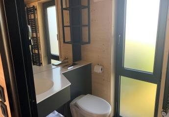 Moderne badeværelse i Tiny House ved Gulperberg, Nederlandene, med store vinduer og trævægge.