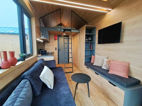 Atractiva casa pequeña en Gulperberg, Países Bajos, con altillo, sala moderna, cocina y sofá azul.