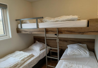Habitación con litera superior y dos camas individuales en Grandeur Panorama 5, Gulperberg, Países Bajos.