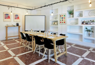 Sala riunioni al TAIGA Conil, parco vacanze in Andalusia, Spagna, con tavoli in legno moderni e decorazioni.