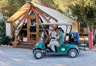 Homme conduisant une voiturette avec valises devant une tente glamping au TAIGA Conil, village vacances en Andalousie, Espagne.