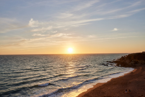 Smuk solnedgang over havet set fra stranden ved TAIGA Conil feriepark i Andalusien, Spanien.