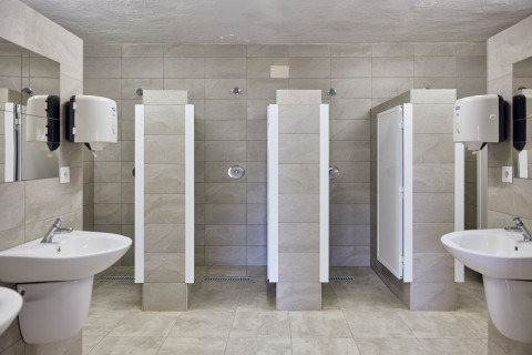 Duchas comunitarias modernas con lavabos y espejos en TAIGA Conil, parque vacacional en Andalucía, España.