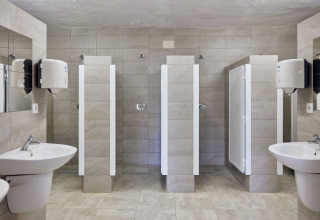 Duchas comunitarias modernas con lavabos y espejos en TAIGA Conil, parque vacacional en Andalucía, España.