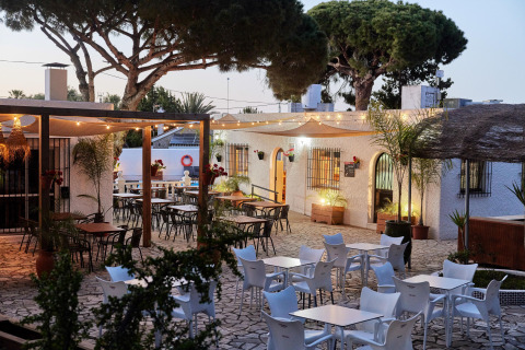 Outdoor dining area at TAIGA Conil holiday park in Andalusia, Spain, featuring lights and trees.