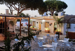 Zona exterior para comer en el parque vacacional TAIGA Conil en Andalucía, España, con luces y árboles.