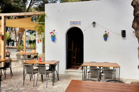 Zona exterior de comedor en TAIGA Conil, parque vacacional en Andalucía, España, con mesas y sillas.