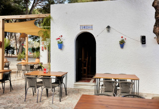 Außenterrasse mit Sitzplätzen im TAIGA Conil Ferienpark in Andalusien, Spanien, sonnig und gemütlich.