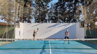 Dos personas jugando al tenis en una pista azul en el parque vacacional TAIGA Conil, Andalucía, España.