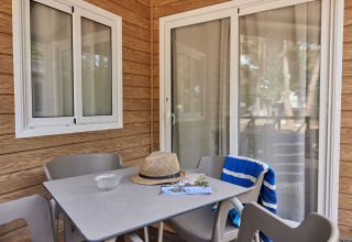Mesa y sillas en la terraza del Bungalow Confort Poniente en TAIGA Conil, España, con sombrero y toalla.