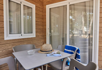Mesa y sillas en la terraza del Bungalow Confort Poniente en TAIGA Conil, España, con sombrero y toalla.