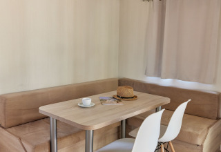 Comedor en Bungalow Confort Poniente en TAIGA Conil, España, con mesa, sillas y banco esquinero.