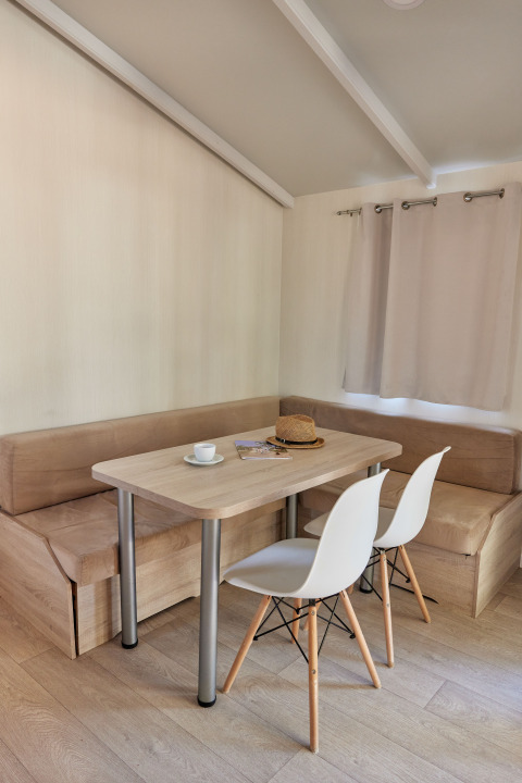 Comedor en Bungalow Confort Poniente en TAIGA Conil, España, con mesa, sillas y banco esquinero.