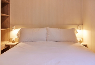 Dormitorio con cama doble y ropa de cama blanca en Bungalow Confort Poniente, TAIGA Conil, España.
