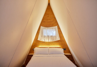 Gezellige slaapkamer in Glamping Tipi Pinar Chalet bij TAIGA Conil in Spanje met houten muren.