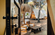 Blick durch eine Tür auf Glamping-Tipis und gemütliche Sitzgelegenheiten bei TAIGA Conil in Spanien.