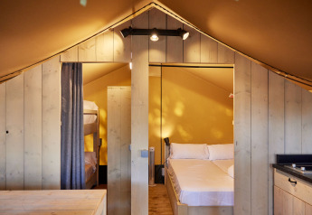 Interno di una tenda glamping Safari con letto matrimoniale e a castello presso TAIGA Conil, Spagna.