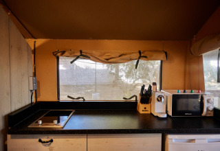 Cocina moderna en la tienda Glamping Safari Mistral de TAIGA Conil en España, con vitrocerámica y microondas.