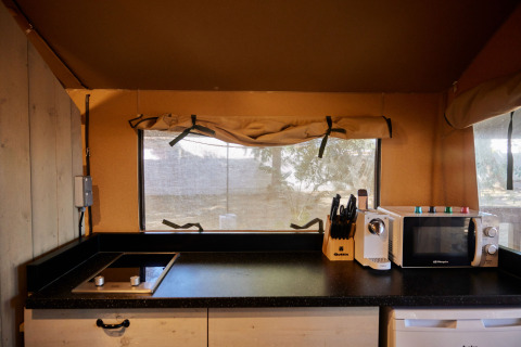 Modern kitchenette inside the Glamping Safari Mistral tent at TAIGA Conil in Spain with stove and microwave.