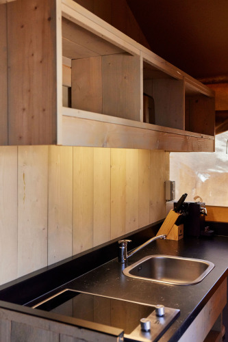 Moderne Küchenzeile im Glamping Safari Siroco Premium Zelt bei TAIGA Conil, Spanien, mit Holzakzenten.