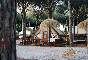 Tentes safari Glamping Tipi Retama à TAIGA Conil, Espagne, nichées dans les arbres avec espaces de repos extérieurs.