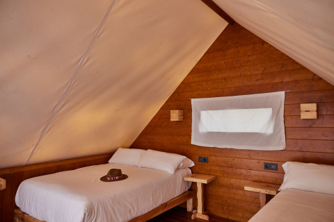 Innenaufnahme eines Glamping-Tipi-Zelts mit zwei Betten und Holzwänden im TAIGA Conil, Spanien