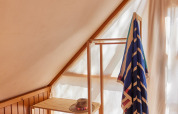 Lumière du soleil dans un coin douillet de la tente Glamping Tipi Retama à TAIGA Conil, avec étagère bois.
