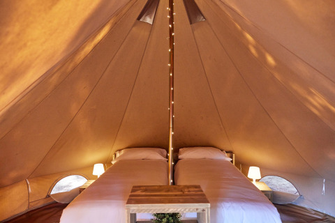 Interieur van de Glamping Bell Marisma tipi tent bij TAIGA Conil, Spanje, met twee gezellige bedden.