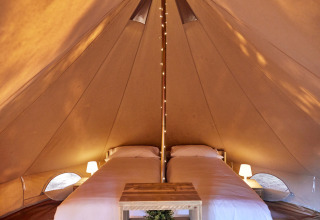 Interno della tenda teepee Glamping Bell Marisma al TAIGA Conil, Spagna, con due letti singoli.