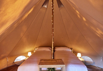 Interno della tenda teepee Glamping Bell Marisma al TAIGA Conil, Spagna, con due letti singoli.