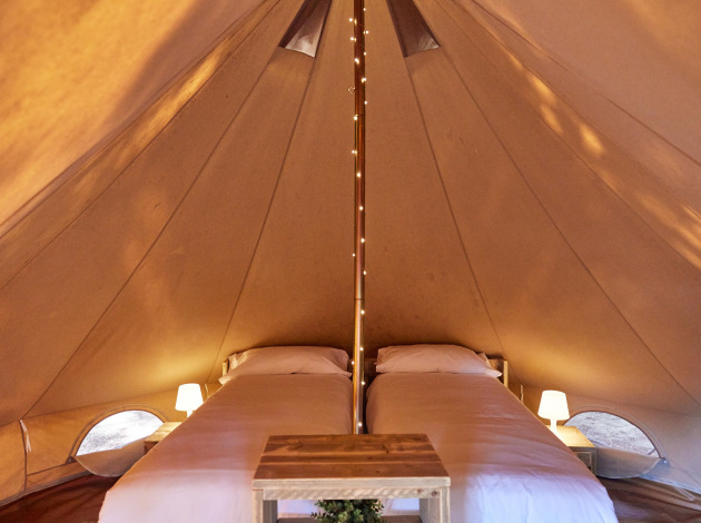 Binnenkant van de Glamping Bell Marisma tipi tent bij TAIGA Conil, Spanje, met twee eenpersoonsbedden.