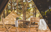 Blick aus dem Zelt auf Holzmöbel und das Glamping Bell Marisma bei TAIGA Conil, Spanien.