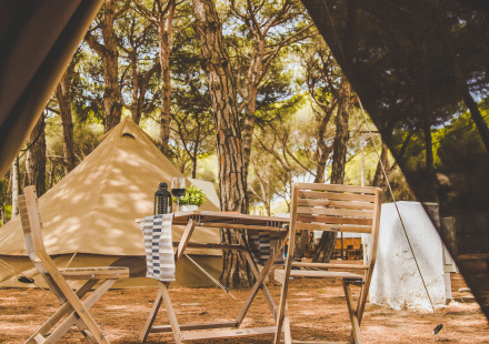 Uitzicht vanuit een tent op houten stoelen en de Glamping Bell Marisma tent bij TAIGA Conil, Spanje.