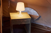 Innenansicht des Glamping Bell Marisma Tipi-Zeltes bei TAIGA Conil, Spanien, mit Nachttisch und Lampe.