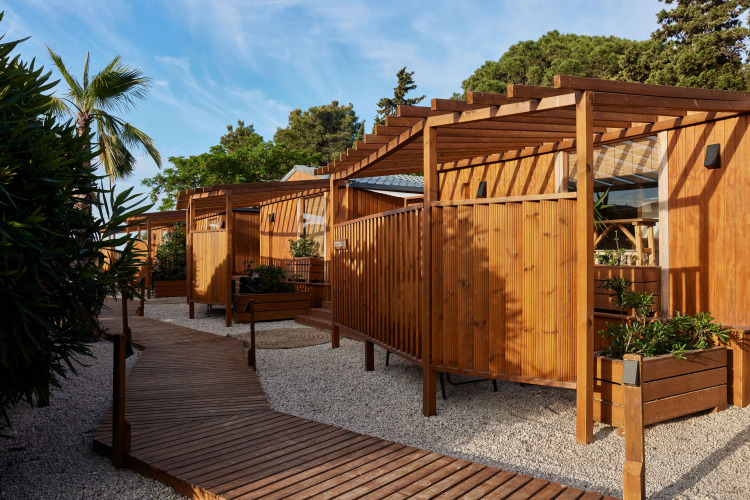 Udendørs billede af træbungalows ved Bungalow Premium Levante med terrasse og grønne planter under blå himmel.