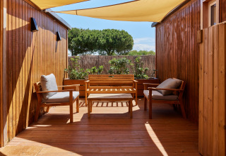 Terraza exterior con muebles de madera y toldo en Bungalow Premium Levante de TAIGA Conil, España.