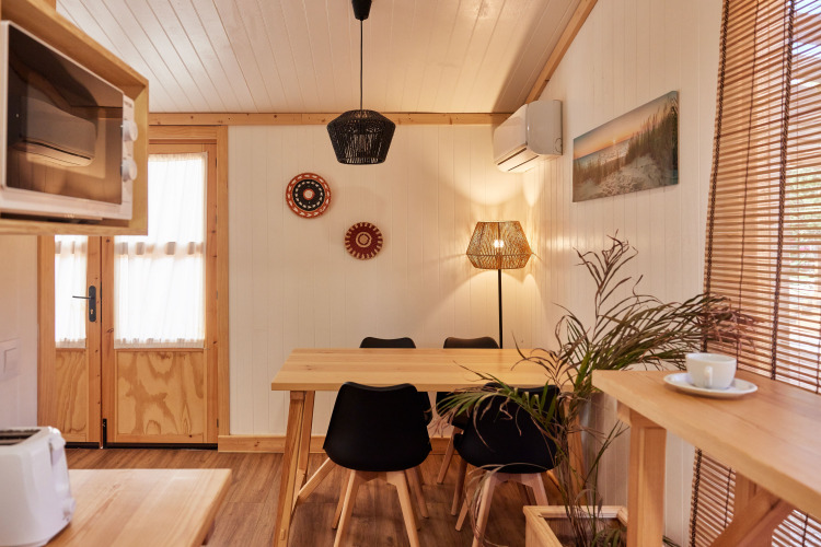 Hyggeligt interiør i Bungalow Premium Levante på TAIGA Conil, Spanien, med spisebord og naturligt lys.