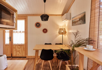 Hyggeligt interiør i Bungalow Premium Levante på TAIGA Conil, Spanien, med spisebord og naturligt lys.