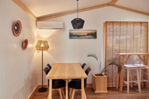 Eethoek in Bungalow Premium Levante bij TAIGA Conil in Spanje, met houten meubels en sfeerverlichting.