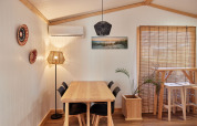 Comedor en Bungalow Premium Levante de TAIGA Conil, España, con muebles de madera y luz natural suave.