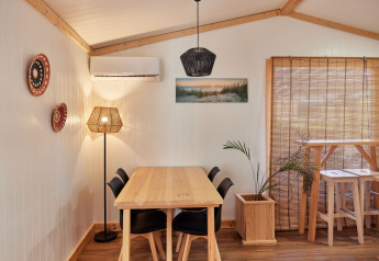 Spiseområde i Bungalow Premium Levante på TAIGA Conil, Spanien, med træmøbler og naturlig belysning.