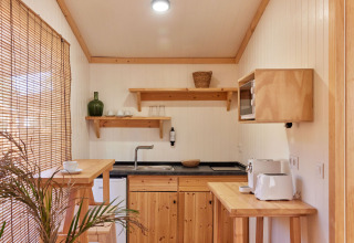 Pequeña cocina en Bungalow Premium Levante de TAIGA Conil, España, con decoración y muebles de madera.