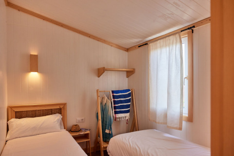 Lichte kamer met twee enkele bedden in Bungalow Premium Levante, TAIGA Conil, Spanje, sobere inrichting.