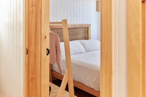 Zicht op een gezellige slaapkamer met houten details in Bungalow Premium Levante, TAIGA Conil, Spanje.