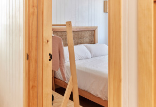 Vista de un dormitorio acogedor con detalles de madera en Bungalow Premium Levante, TAIGA Conil, España.